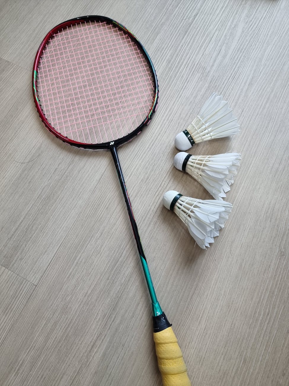 photo of a badminton racket near shuttlecocks