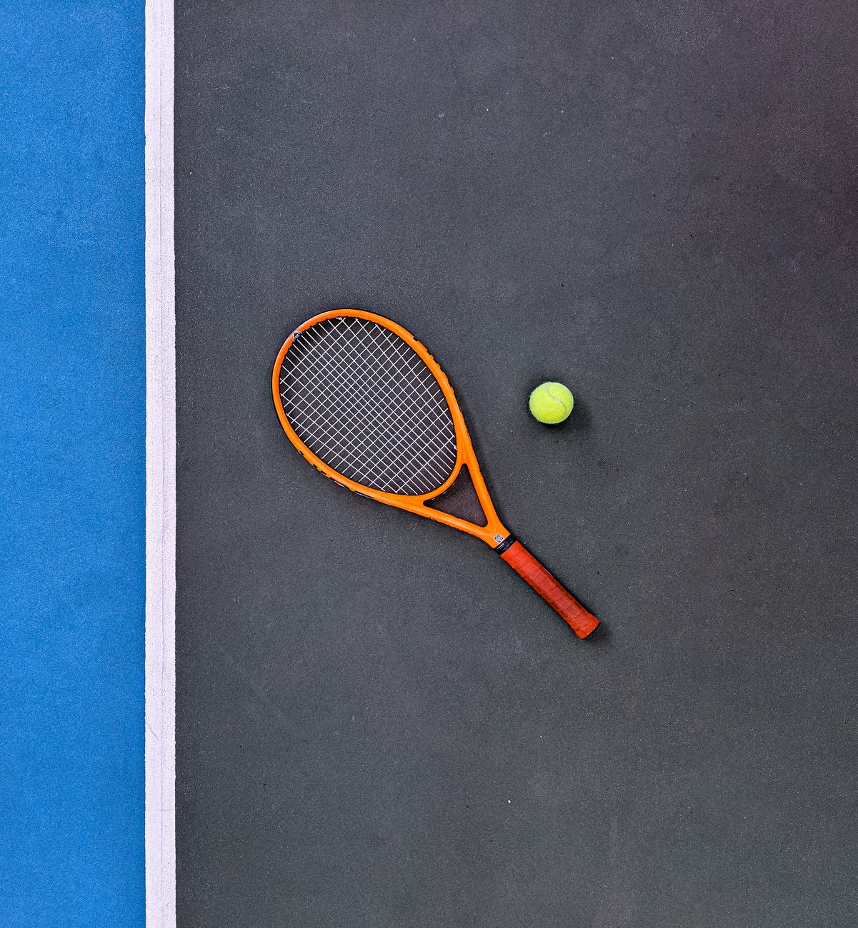 orange tennis racket beside green tennis ball